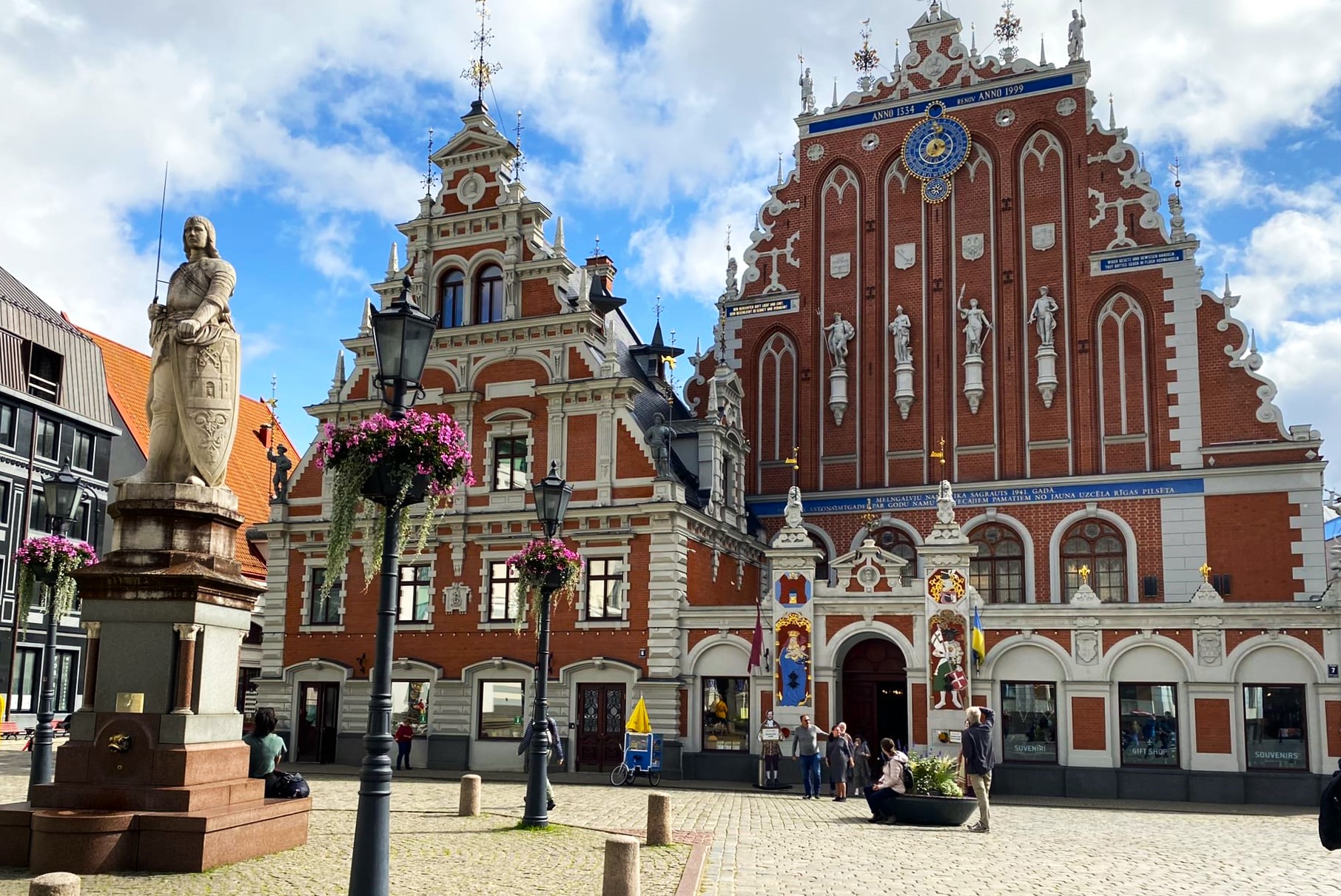 Fachada Histórica De La Casa De Los Cabezas Negras En El Casco Antiguo De Riga, Letonia, Con Una Estatua De Un Caballero En Primer Plano, Reflejando El Entorno Urbano De Las Ciudades Donde Operan Los Servicios De &Quot;Maridos Por Hora&Quot;.