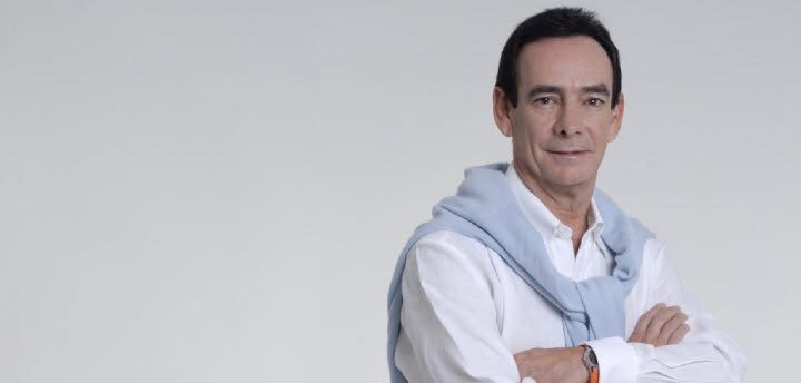 Retrato Corporativo De Carlos Salomón Cámara Con Camisa Blanca Y Suéter Azul, Destacando Su Trayectoria Como Estratega Político Y Experto En Comunicación Desde El Sureste.