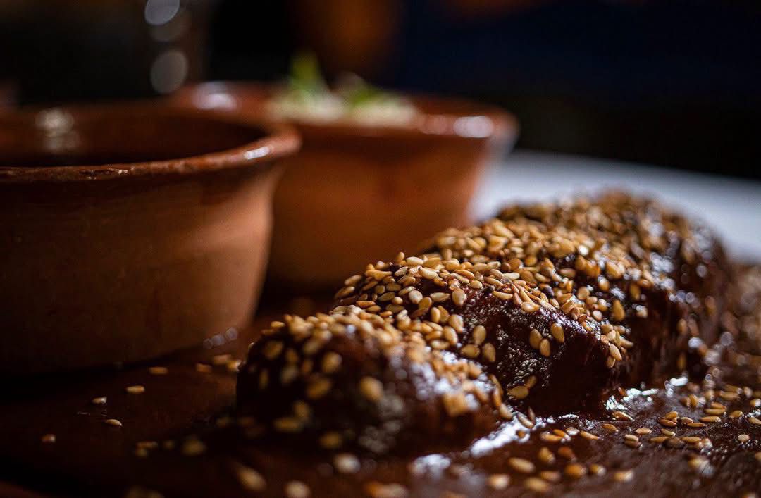 La marquesa se llena de sabores con el primer encuentro gastronómico mexiquense “saberes y sabores de mi tierra” la revista del sureste mx Platillo Tradicional Elaborado Con Mole Oscuro Espolvoreado Con Semillas De Ajonjolí Tostado, Servido Junto A Cazuelas De Barro En El Primer Encuentro Gastronómico Mexiquense.