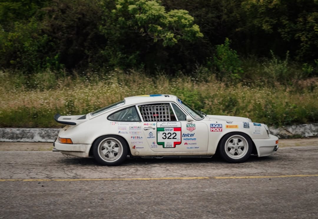 Automóvil Clásico De Competencia Color Blanco Con El Número 322 Circulando Por Una Carretera Pavimentada Rodeada De Vegetación.