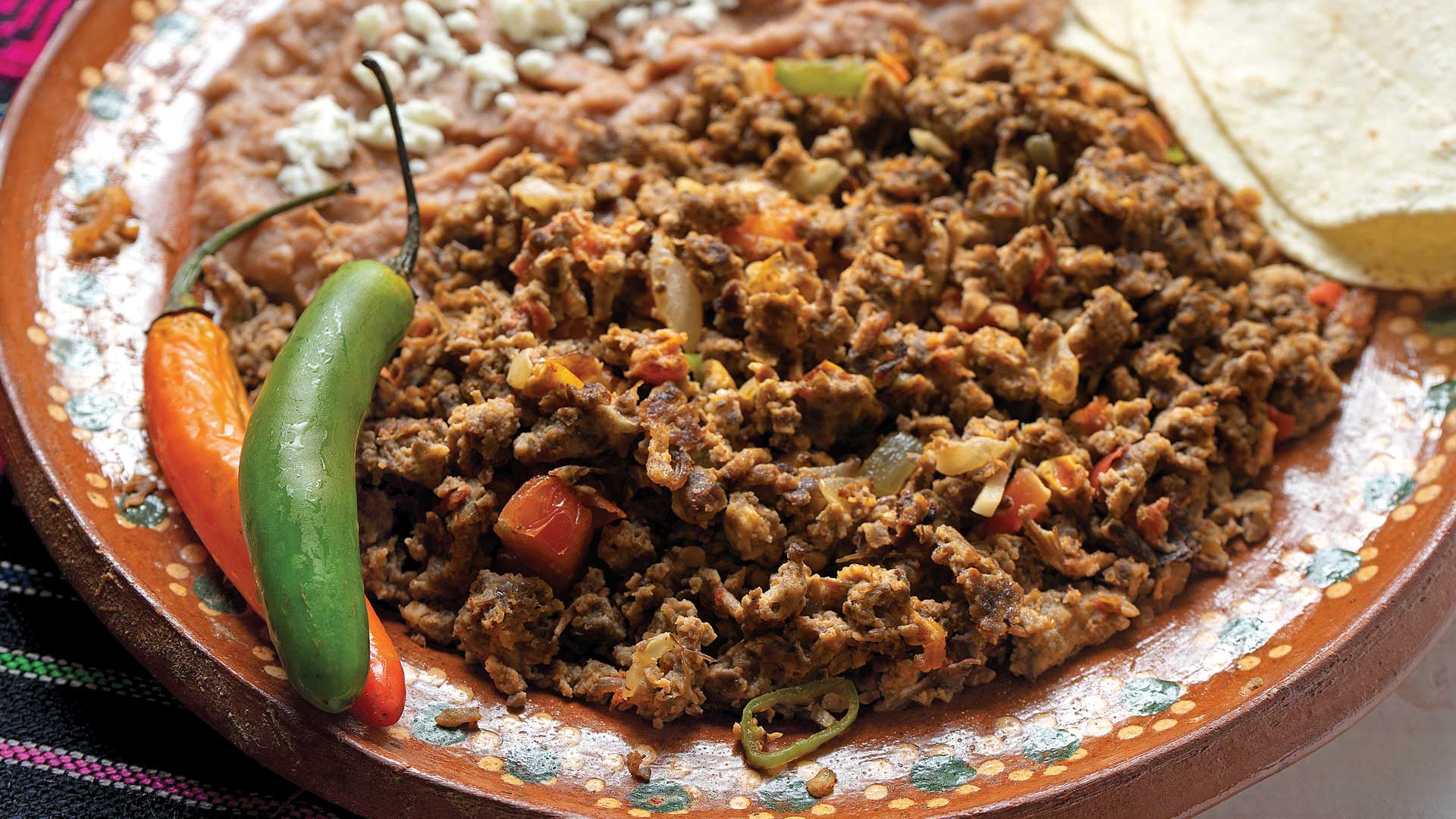 Sabor y tradición norteña: las 5 joyas gastronómicas que debes probar en tu visita a monterrey la revista del sureste mx Plato Artesanal De Barro Con Machacado Con Huevo Preparado Con Verduras, Acompañado De Frijoles Refritos Con Queso Espolvoreado, Tortillas De Harina Y Chiles Serranos Enteros.
