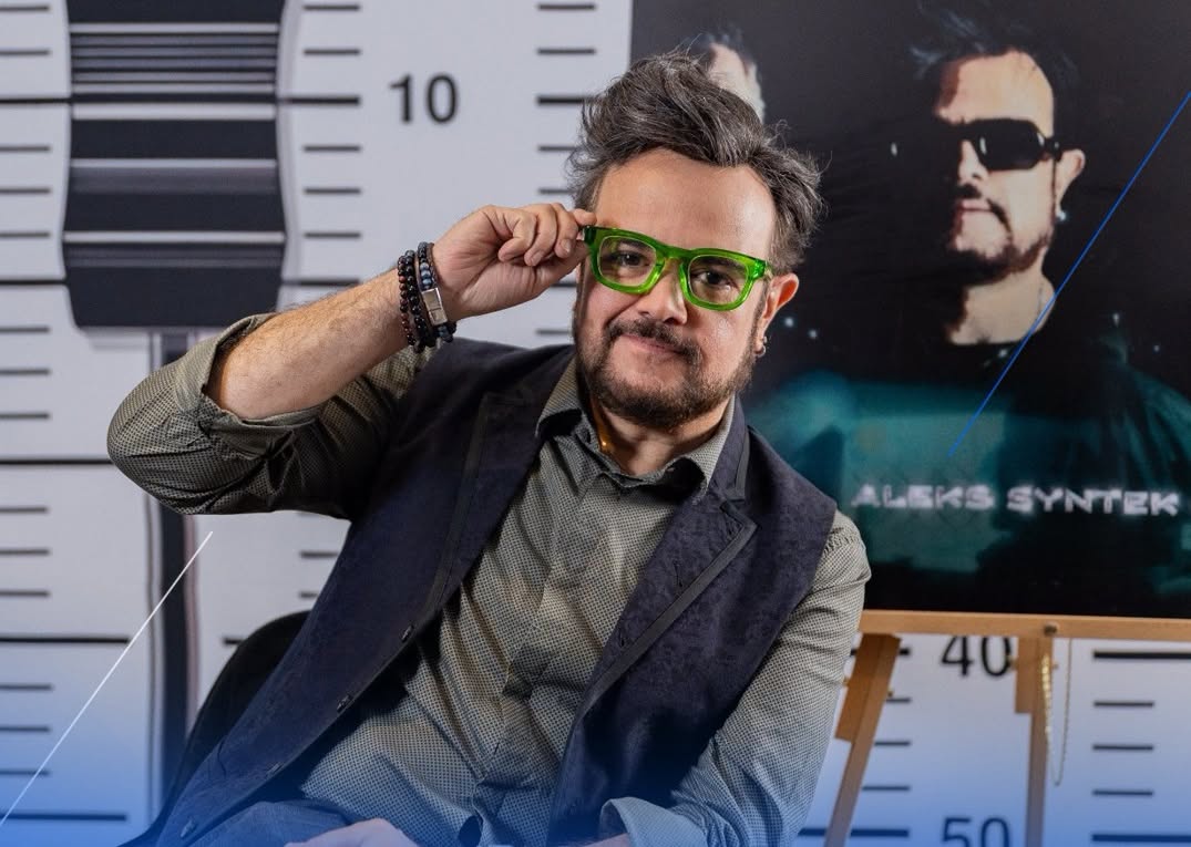 Retrato Del Cantante Aleks Syntek Escándalos Y Polémicas, Posando Frente A Un Fondo Decorado Con Una Regla Métrica O De Fichaje.