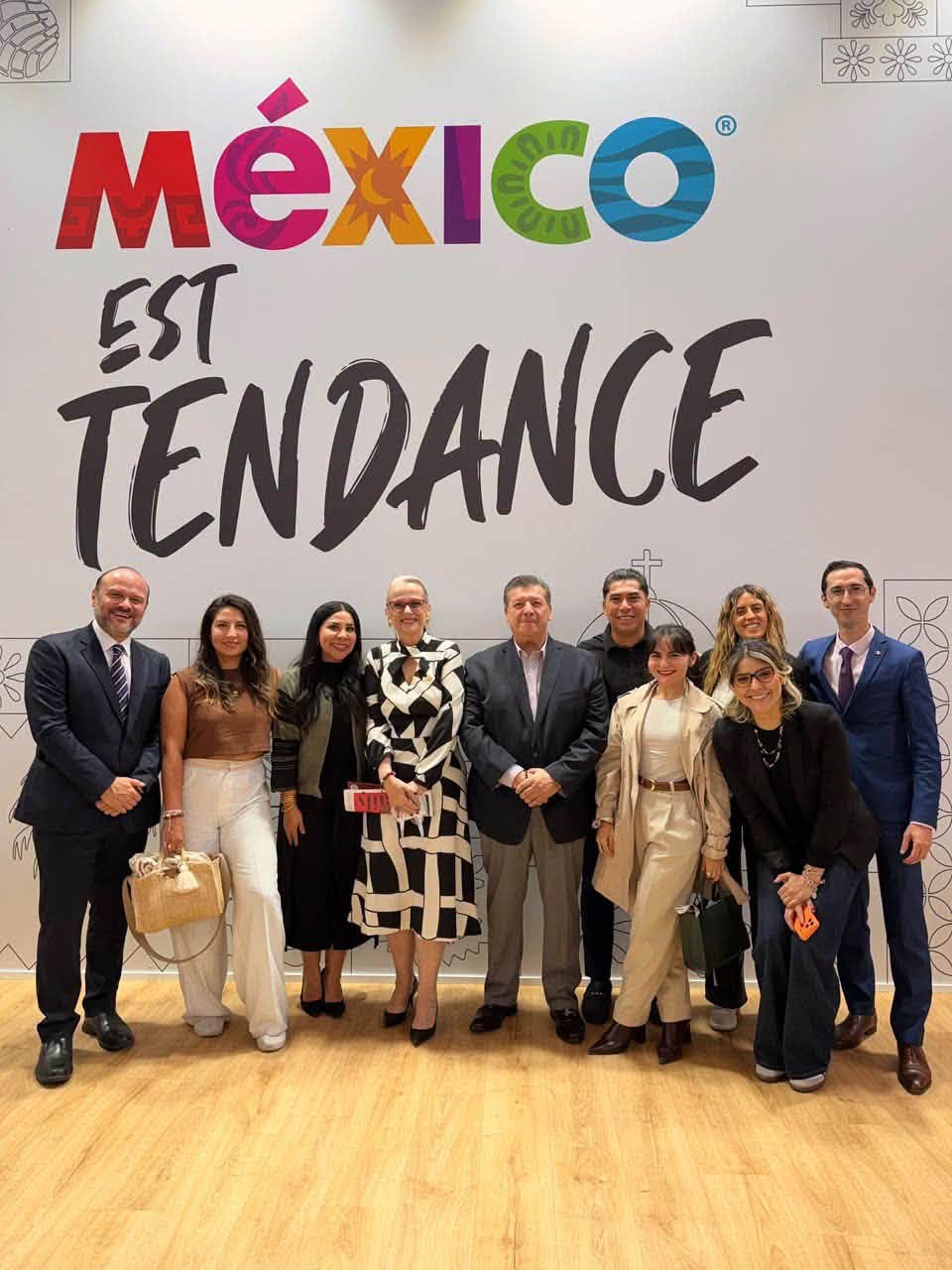 Delegación Oficial De México Celebrando Que El País Invitado De Honor De Iftm Top Resa 2027 Será México, Posando Frente A Un Muro Con La Leyenda &Quot;México Est Tendance&Quot;