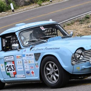 Automóvil Clásico De Competencia Color Azul Celeste Con El Número 253 Participando En La Carrera Panamericana Sobre Una Carretera Asfaltada.